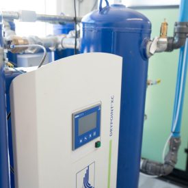 BEKO DRYPOINT XC compressed air dryer system with blue pressure vessel and connected pipes in a bright industrial room.