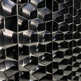 Close-up of a black honeycomb-shaped grid pattern, showing repeating hexagonal cells in a geometric arrangement.